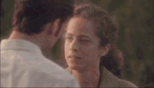 a man and a woman are looking at each other with trees in the background
