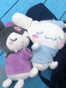 two stuffed animals laying next to each other one of which has a skull on its head