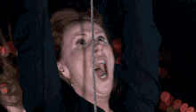 a woman with her mouth open hanging from a rope
