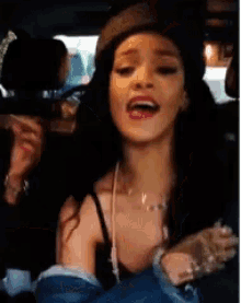 a woman is singing in a car while wearing a hat .