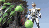 a man in a superhero costume is standing in front of a large green monster .
