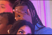 a man is covering his face with his hand while sitting next to a woman .