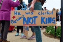 a protester holds a sign that says he was elected president not king