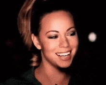 a close up of a woman 's face with a ponytail and smiling .