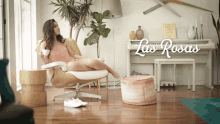 a woman sits in a chair in front of a piano with the words las rosas on the bottom