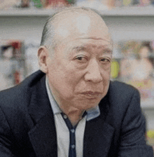 a man in a suit and tie is sitting in front of a bookshelf .