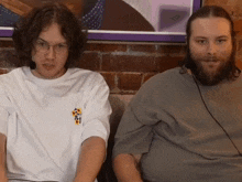 two men are sitting next to each other with one wearing a shirt that says ' a ' on the front