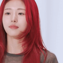a woman with red hair is wearing a black shirt and looking at the camera .