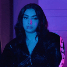 a woman wearing a black jacket with a pink stripe on the sleeves looks at the camera