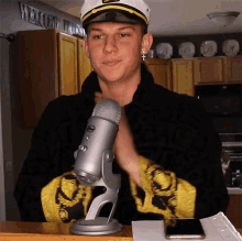 a man wearing a captain 's hat stands in front of a microphone