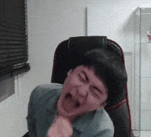 a man is sitting in a chair with his mouth open and his tongue out .