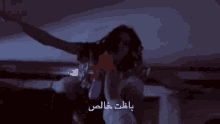 a man is holding a toy in a dark room with arabic writing on the bottom