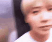 a close up of a person 's face with a blurry background and a white shirt on .