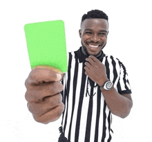 a referee is holding a green card in his hand