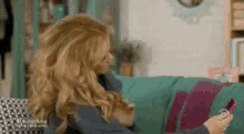 a woman is sitting on a couch looking at her cell phone .