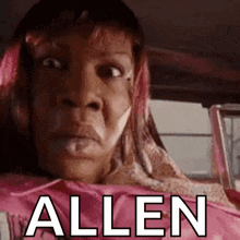 a woman with pink hair is sitting in a car with the word allen written on the side of her face .