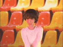 a girl is standing in front of a row of yellow and red chairs