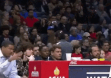 a crowd of people are watching a basketball game with a sign that says anc on it