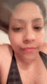 a close up of a woman 's face with a red lip and a black tank top .