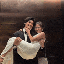 a man is carrying a woman in a white dress in an elevator