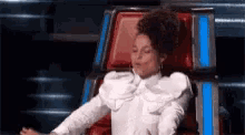 a woman in a white shirt is sitting in a chair with her eyes closed .