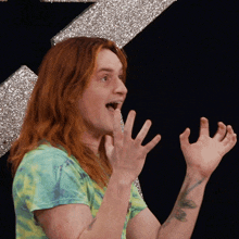 a man with long red hair is making a funny face with his hands in the air