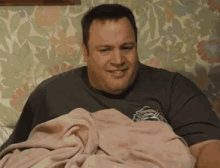 a man is laying in bed with a pink blanket