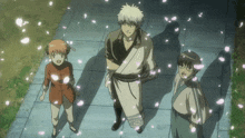 a group of anime characters are standing on a sidewalk with petals falling around them