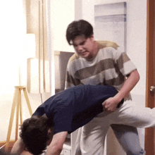 a man in a striped shirt is holding another man 's back