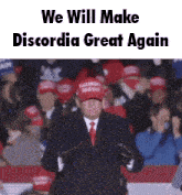 a man in a suit and tie is standing in front of a crowd wearing a maga hat and gloves .