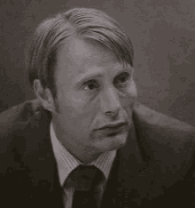 a black and white photo of a man wearing a suit and tie .