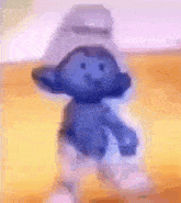 a smurf toy is dancing on a wooden floor .