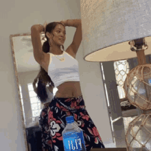 a woman stands in front of a mirror next to a bottle of aquafina