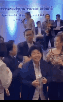 a group of people are sitting in a room with a man playing a saxophone and a woman singing .