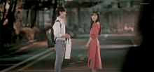 a man and a woman are standing next to each other on a street