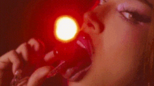 a close up of a woman 's mouth with a red light behind her .