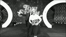 a black and white photo of a man and a woman in front of a sign that says tony stark