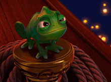 a green chameleon sitting on top of a rope