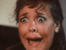 a woman is making a funny face with her mouth open and her eyes wide open .