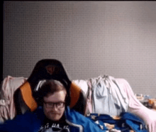 a man wearing glasses and headphones is sitting on a couch .