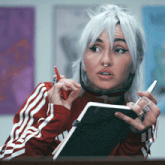 a woman with white hair and a nose ring is holding a pen and a notebook
