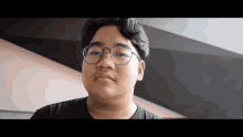 a man wearing glasses and a black shirt looks at the camera