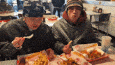 a man wearing a bandana that says yankees is sitting at a table eating french fries