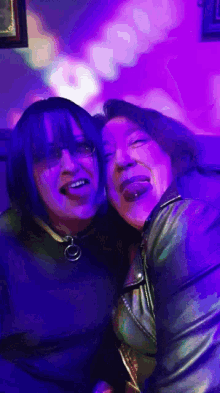 two women sticking their tongues out in a dark room