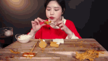 a woman in a red sweater is sitting at a table eating fried food