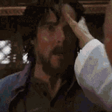 a man with a beard is scratching his forehead .