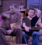 a group of men are sitting on a couch playing a game on a laptop computer .