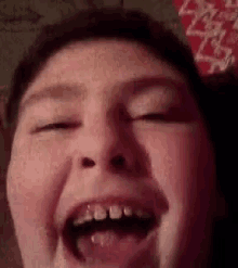 a close up of a child 's face with his eyes closed and his mouth open .
