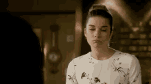 a woman in a white dress is making a funny face while standing in front of a clock .