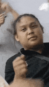 a woman in a black shirt is making a funny face while holding a pen in her hand .